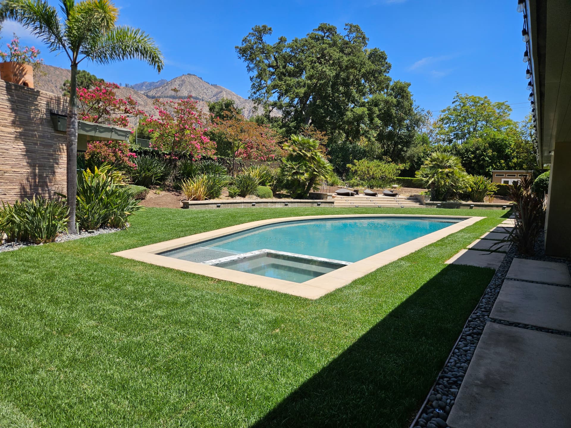 Sail shaped geometric pool with in pool spa set into a level lawn