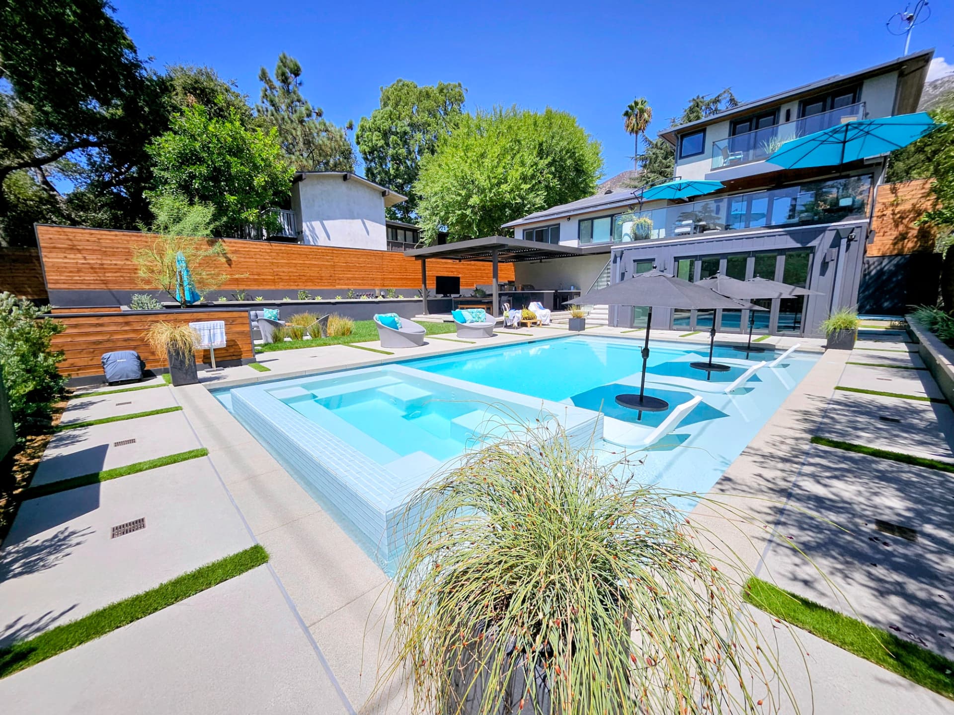 Resort style pool, spa and sun shelf with a modern pool house